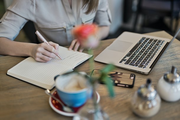 person-writing-on-a-notebook-beside-macbook-1766604.jpg