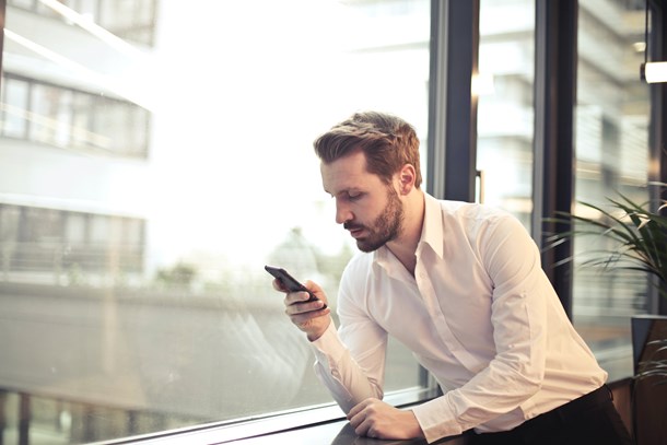 photo-of-man-in-white-dress-shirt-holding-phone-near-window-859265.jpg