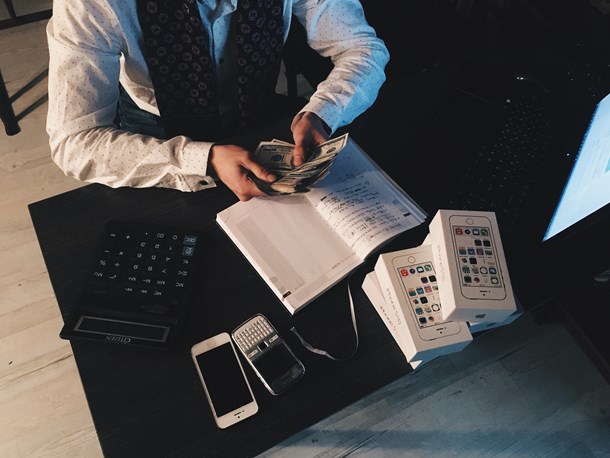 person-counting-money-with-smartphones-in-front-on-desk-210990.jpg
