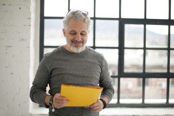 cheerful-mature-male-employee-holding-documents-against-3931608.jpg