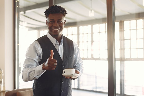 smiling-young-ethnic-businessman-standing-in-cafe-with-cup-3873745.jpg